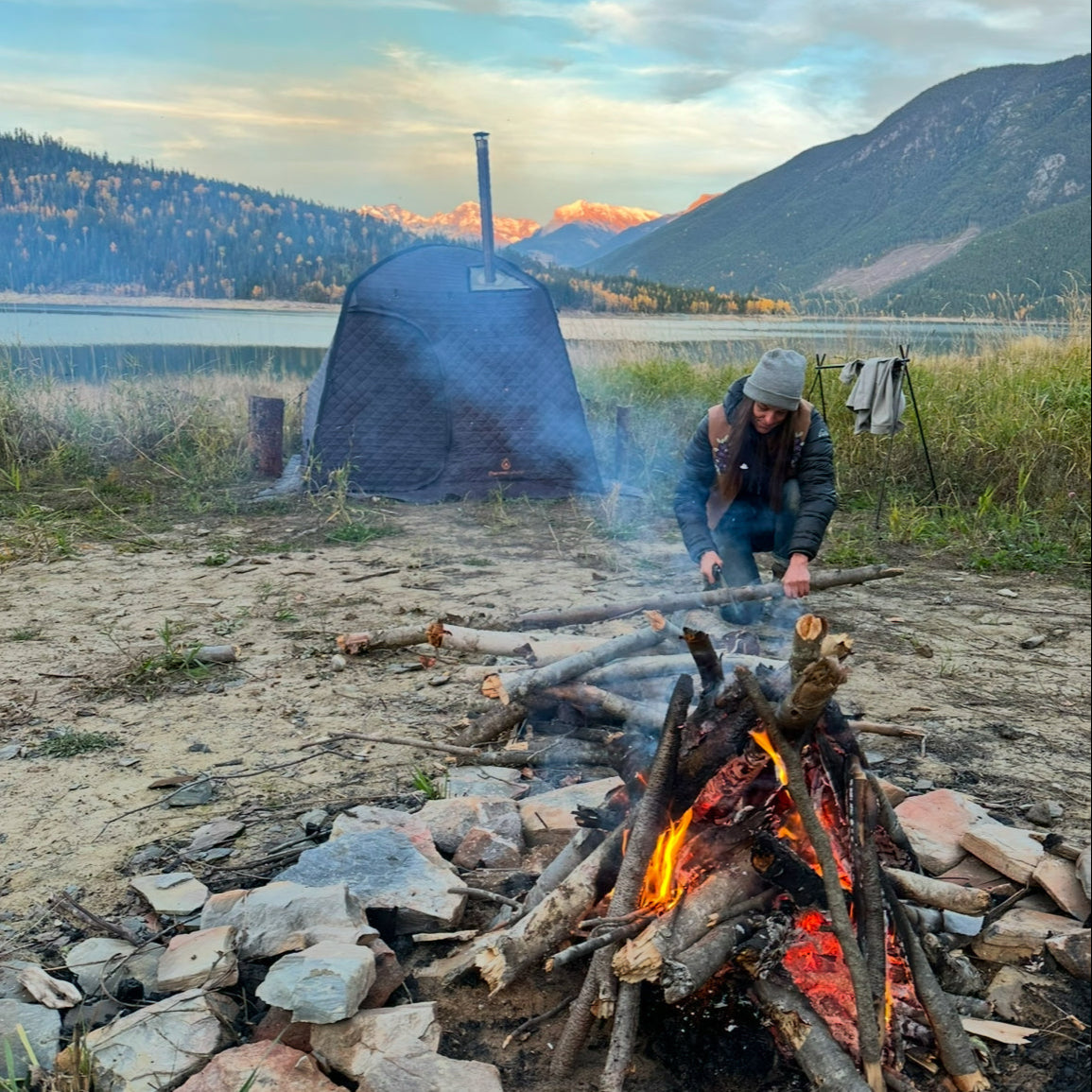 Thermaculture Founder Amanda stoking a fire in front of the Thermaculture sauna tent