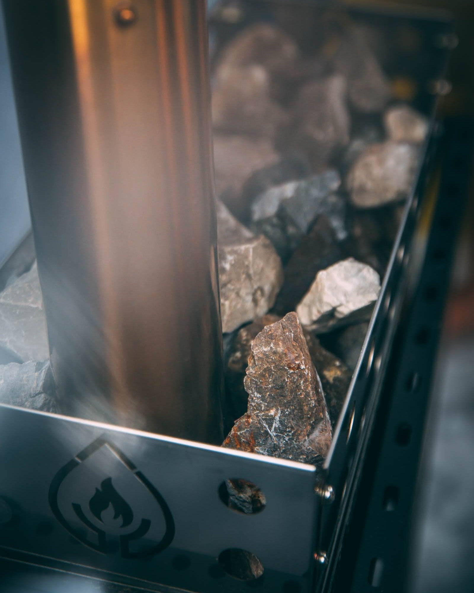 Close-up of a metal sauna wood-fired stove with sauna rocks and steam