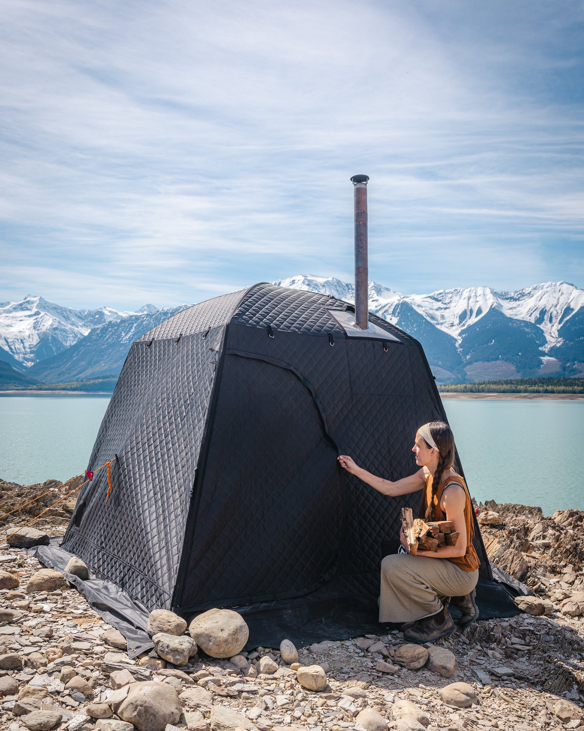 Thermaculture portable sauna tent used outdoors by a lake, wood-fired sauna setup with mountain scenery.